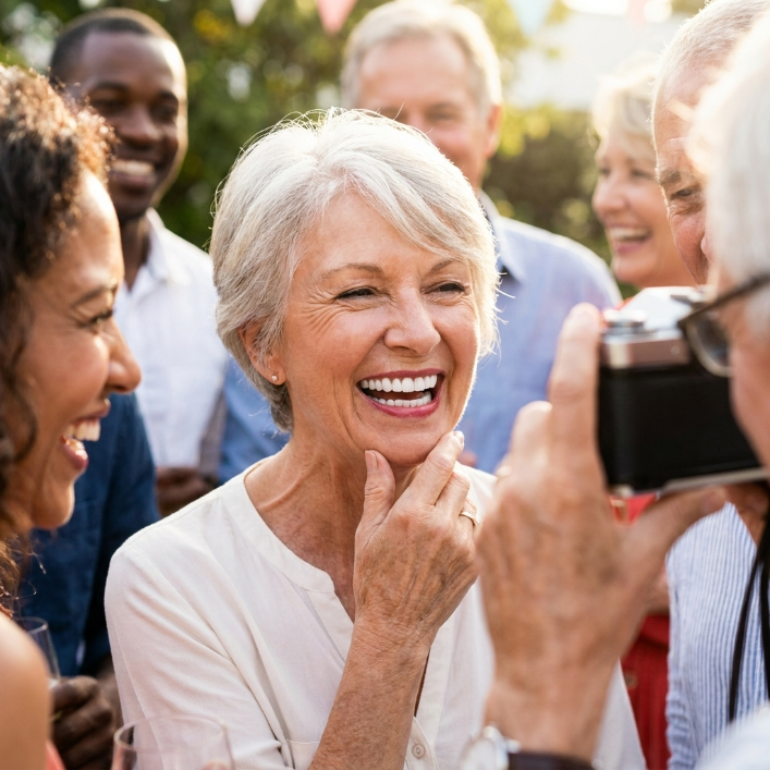 Persona mayor radiante con sonrisa transformada en ambiente social
