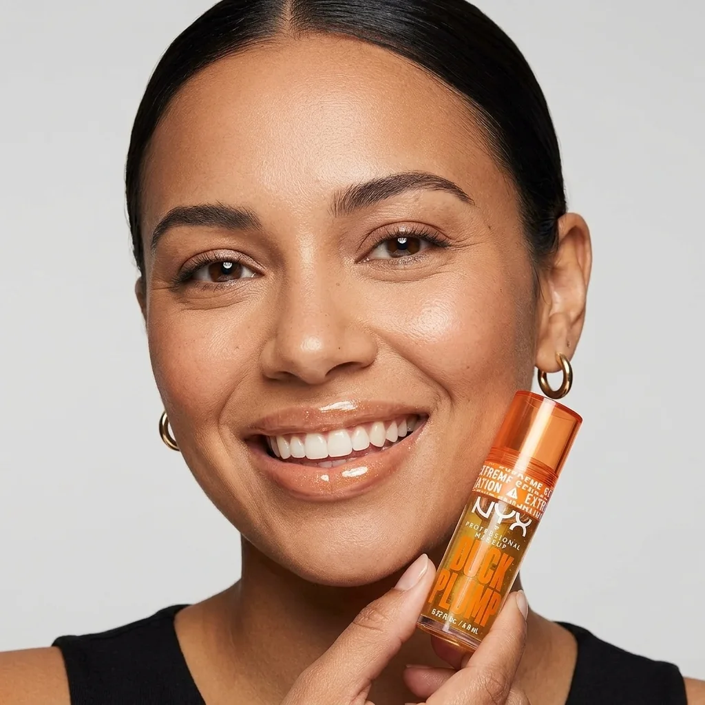 Mujer sonriente con labios brillantes sujetando el gloss voluminizador