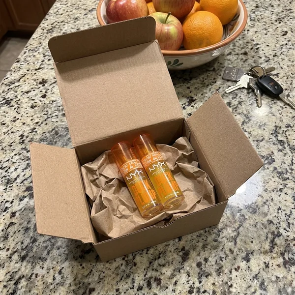 Foto de la clienta: caja del pedido abierta en la encimera de la cocina con los dos glosses