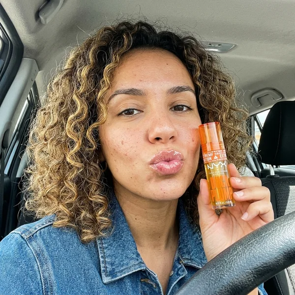 Selfie de la clienta en el coche sujetando el gloss voluminizador