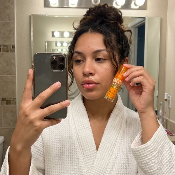 Selfie de la clienta en el espejo del baño sujetando el gloss